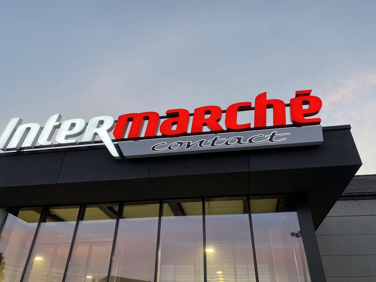 La façade de l'Intermarché Contact de Gedinne au coucher du soleil